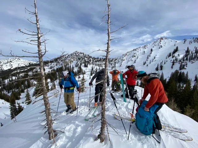 Ski tourers regrouping on a ridge with the Wasatch peaks behind them