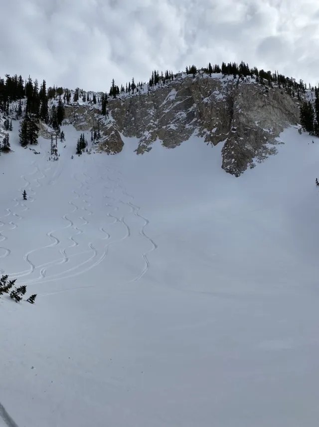 Snowy basin below a rocky cliff band